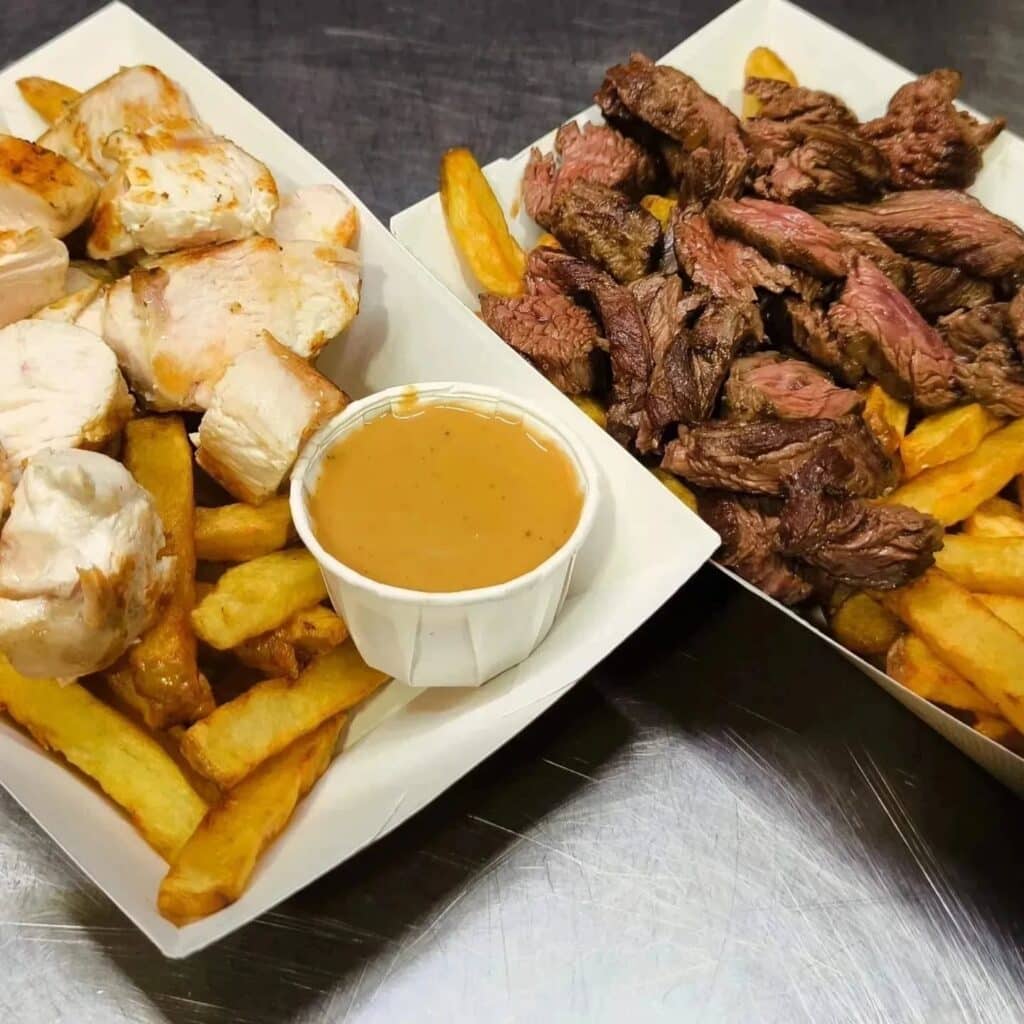 Poulet, Steak Frites et Sauce en Barquette Deux barquettes de plats à emporter : poulet grillé et frites avec sauce d'un côté, et steak coupé en lanières et frites de l'autre.